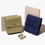 an olive green and a blue custom stand-up jewelry pouch with button closures, separately standing against two beige slate, with a pair of gold earrings in front of them.