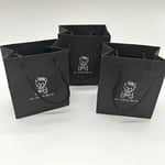 the front of three custom black gift paper bags from the overlook angle