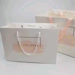 two custom white paper bags with rope handles and ribbon handles